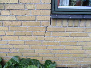 Revne i mur under vindue inden stabilisering med skruepæle