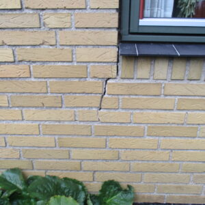 Revne i mur under vindue inden stabilisering med skruepæle